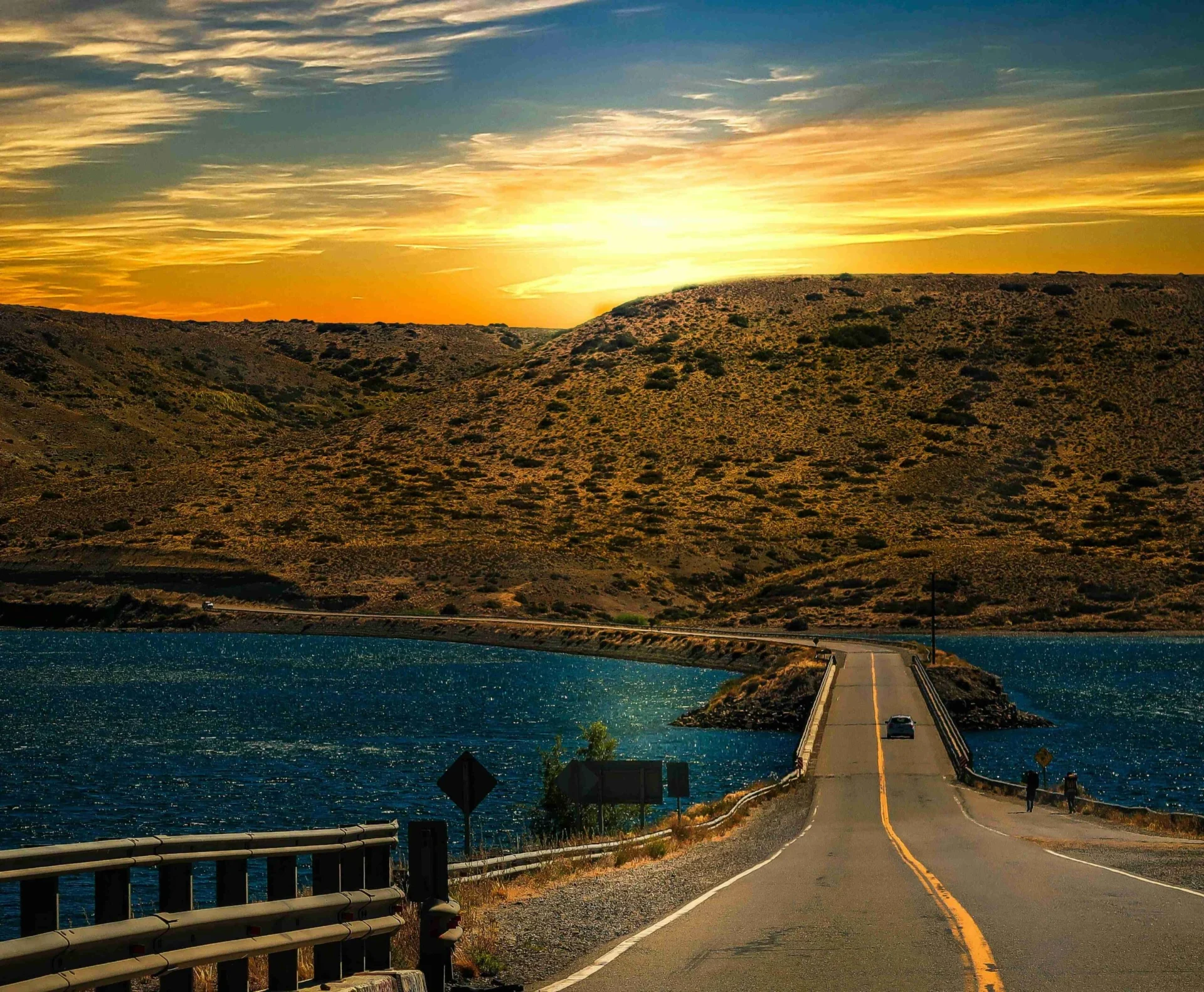 an empty road surrounded by trees with mountains
